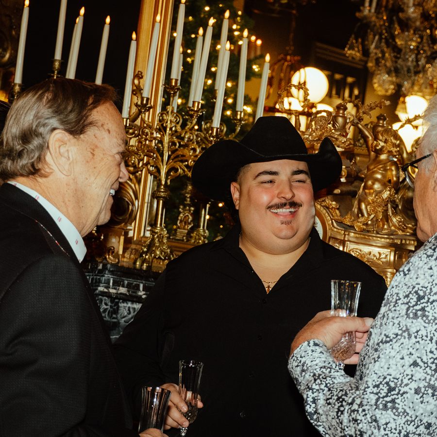 Deux convives un verre à la main sous les candélabres du grand salon