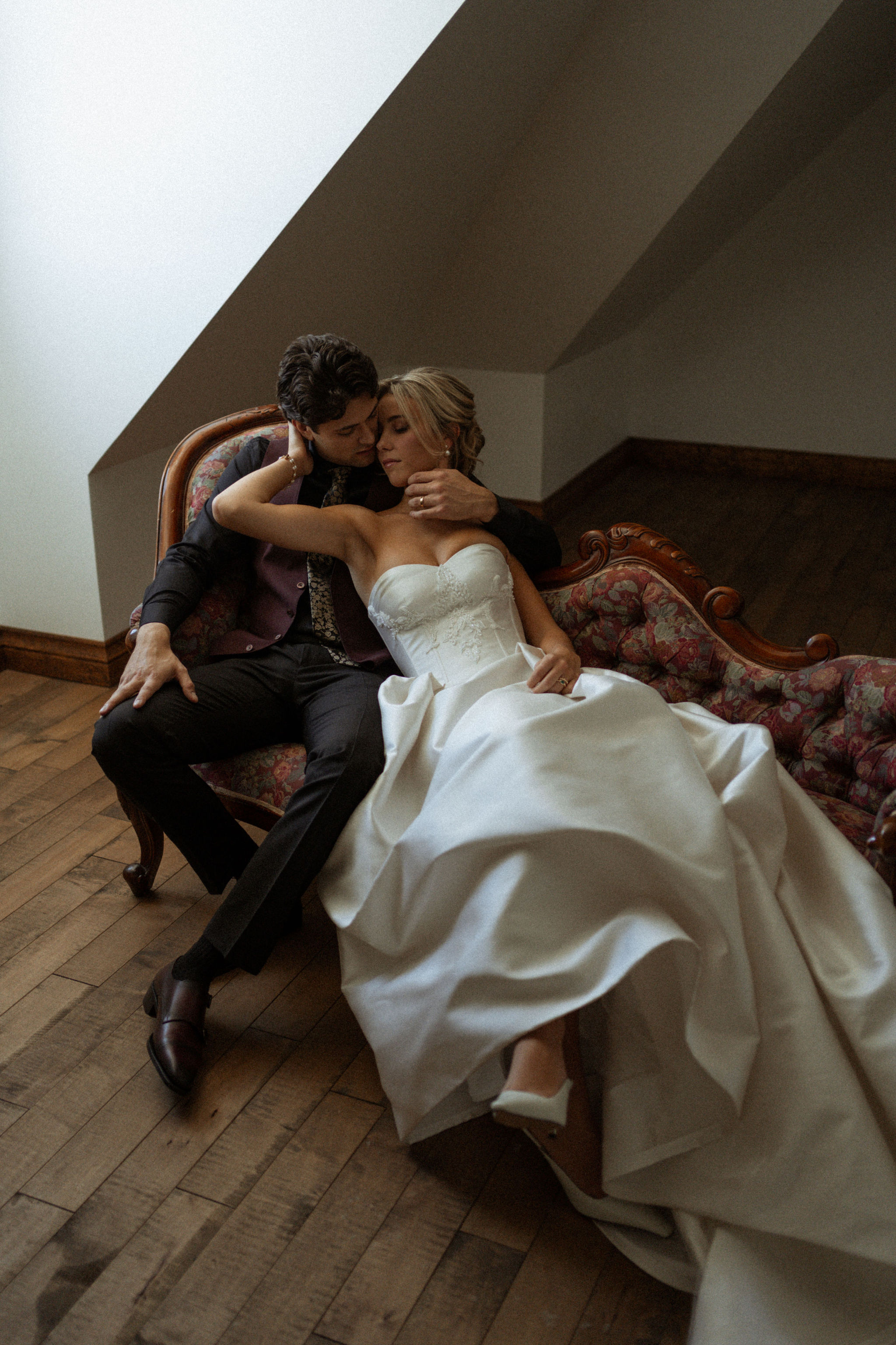 Couple de mariés enlacé sur un fauteuil ancien au Manoir Blackswan