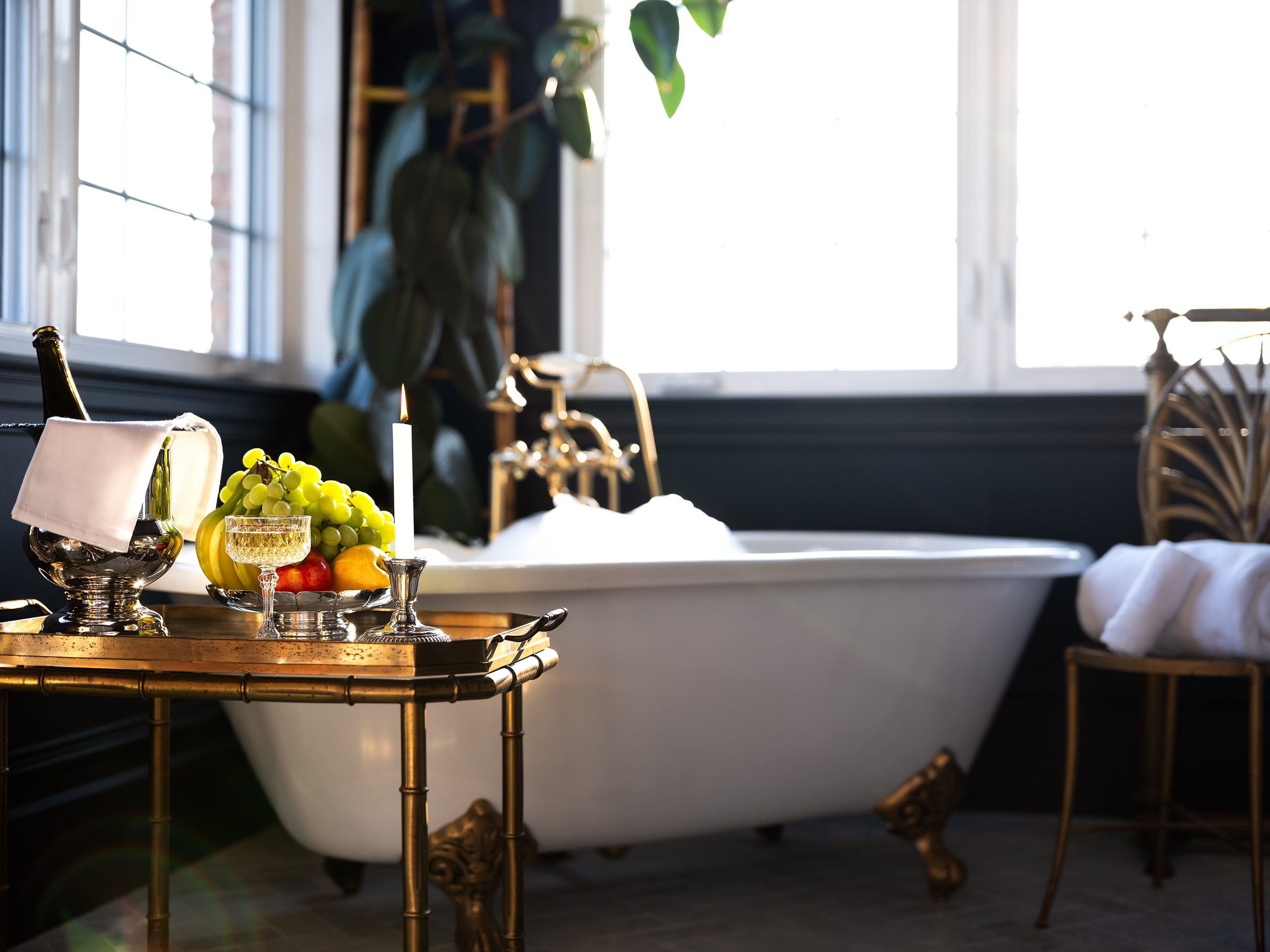 Une baignoire sur pieds du Manoir Blackswan, avec champagne et fruits sur une desserte de laiton