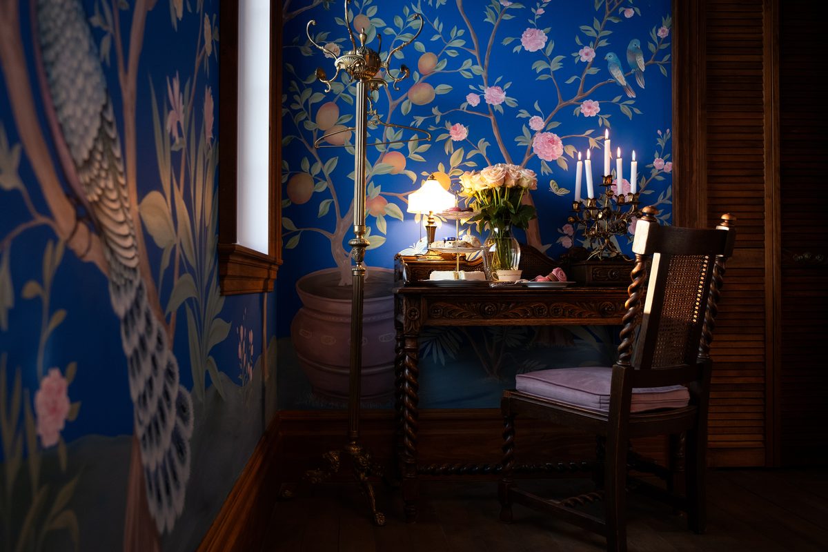 Le secrétaire de la chambre Lán, candélabre et bouquet devant la chinoiserie au paon