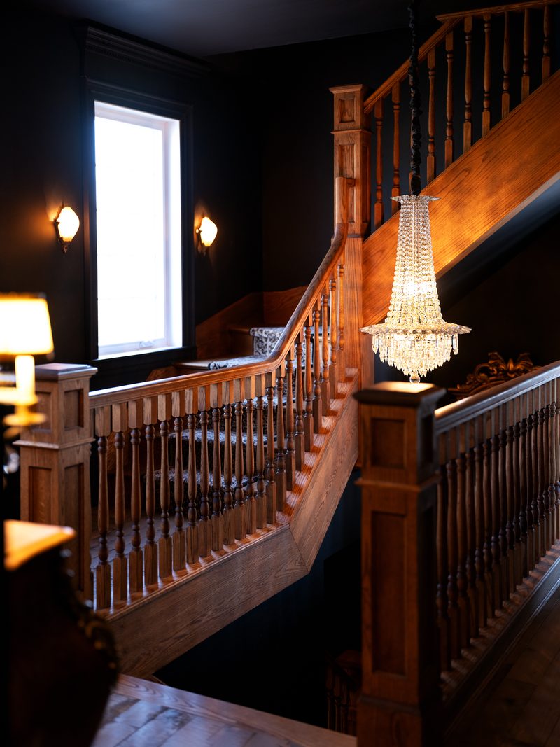 L'escalier de bois du manoir et son lustre de cristal, entre deux étages