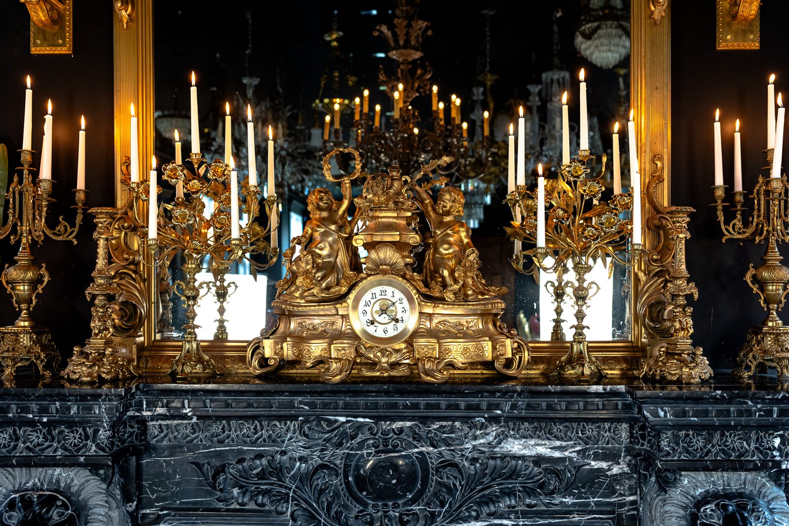 Pendule ancienne et candélabres dorés sur une cheminée de marbre noir du Manoir Blackswan