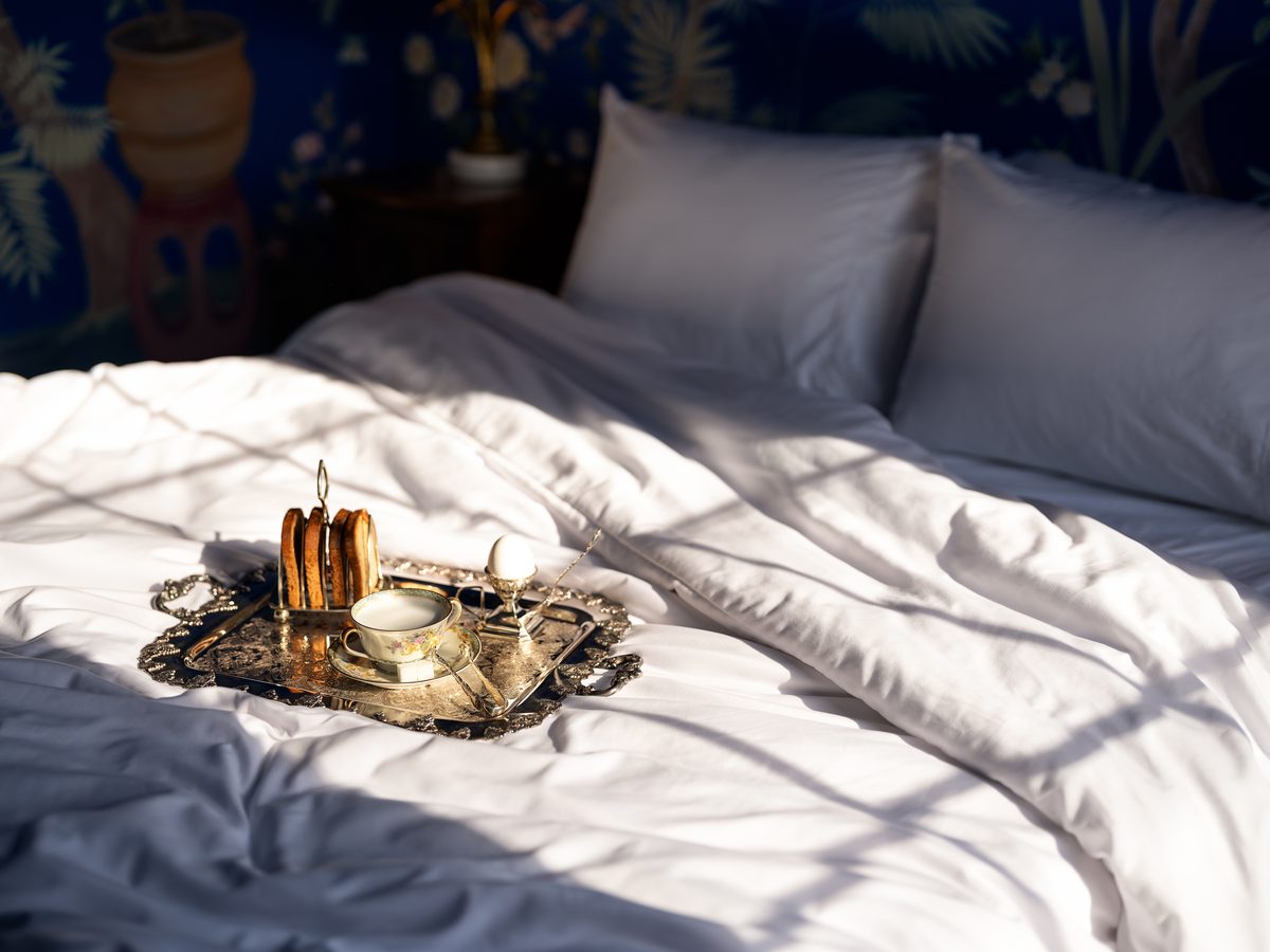Un plateau de petit-déjeuner en argent posé sur le lit de la chambre Lán