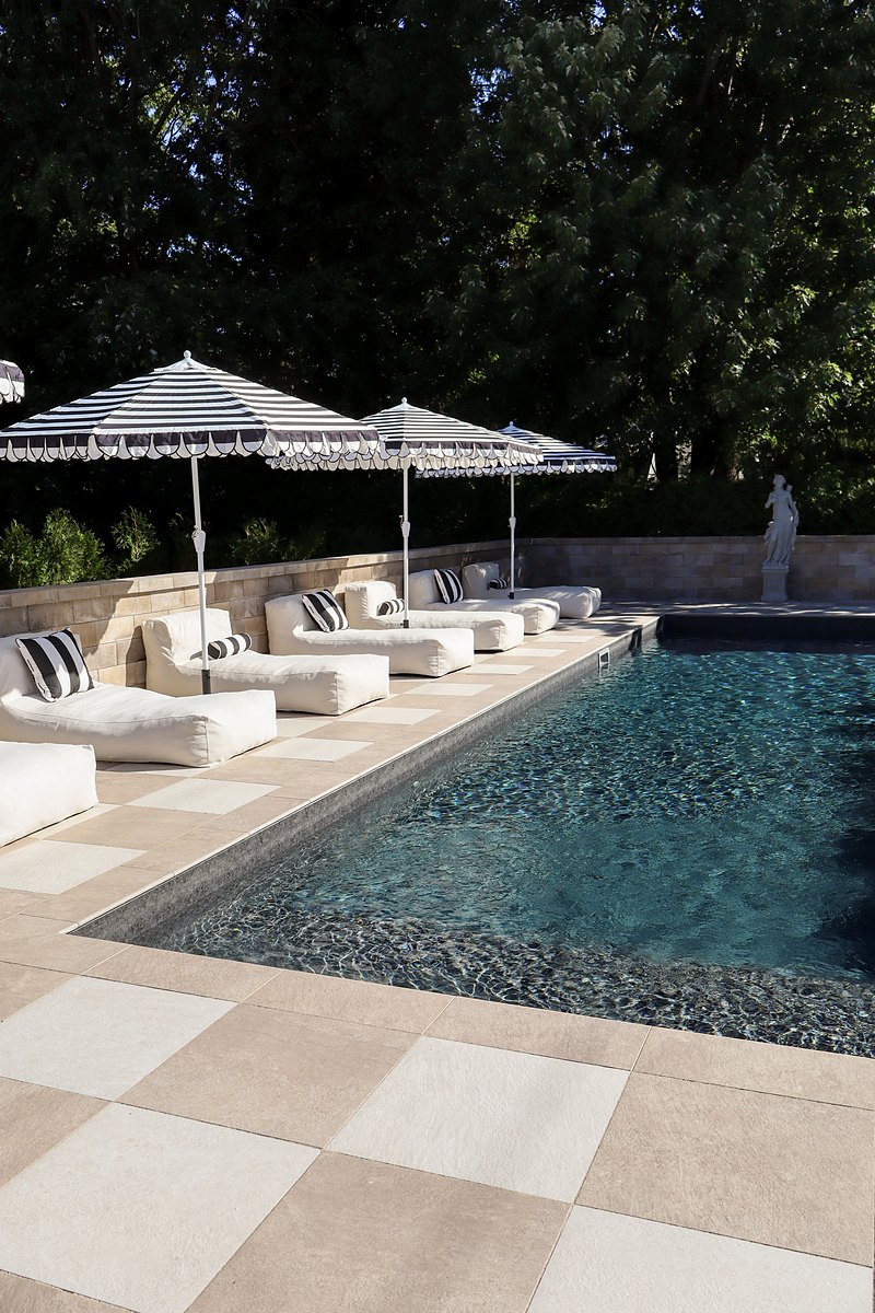 La piscine creusée du Manoir Blackswan, ses chaises longues et ses parasols rayés