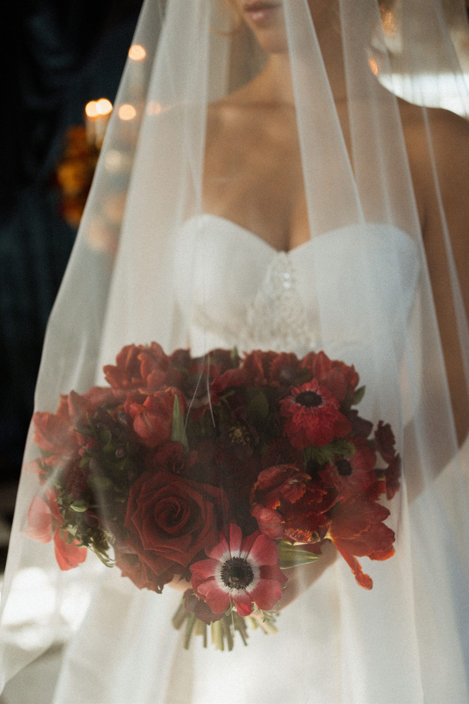 Bouquet de mariée aux fleurs rouges sous le voile