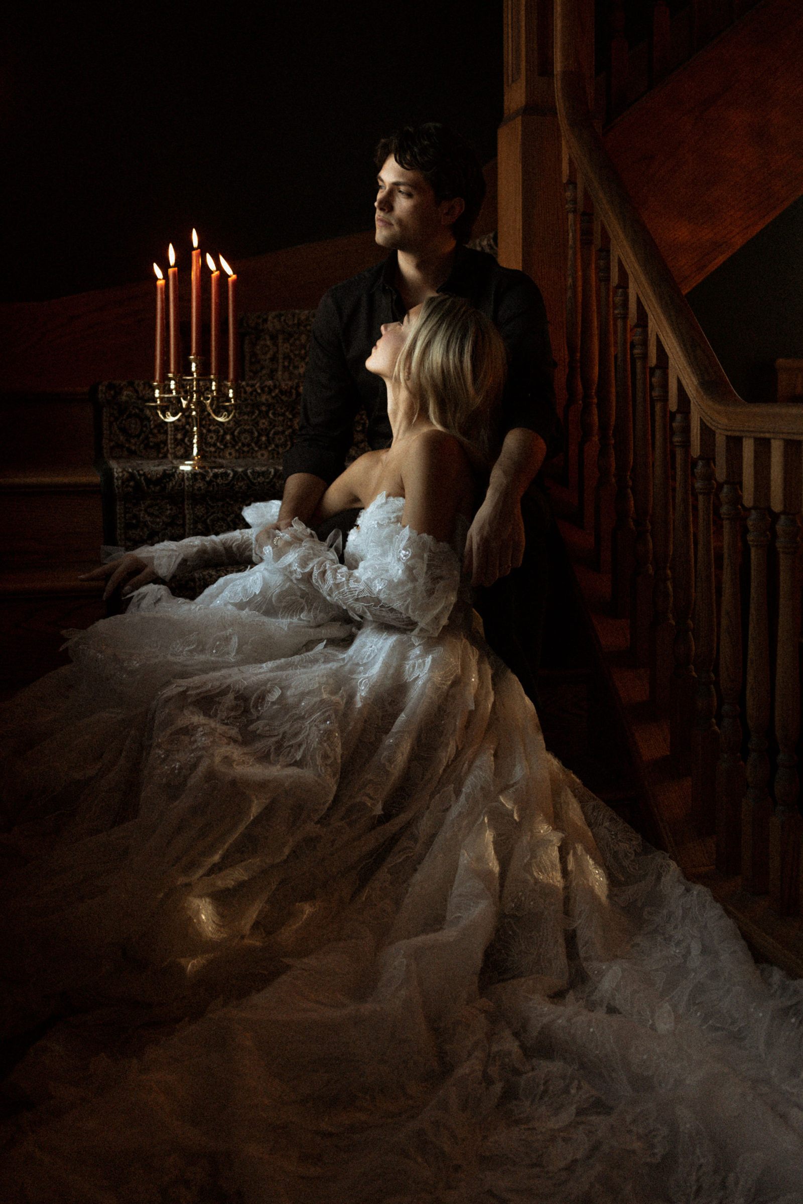 Couple de mariés dans l'escalier du manoir, éclairé à la chandelle