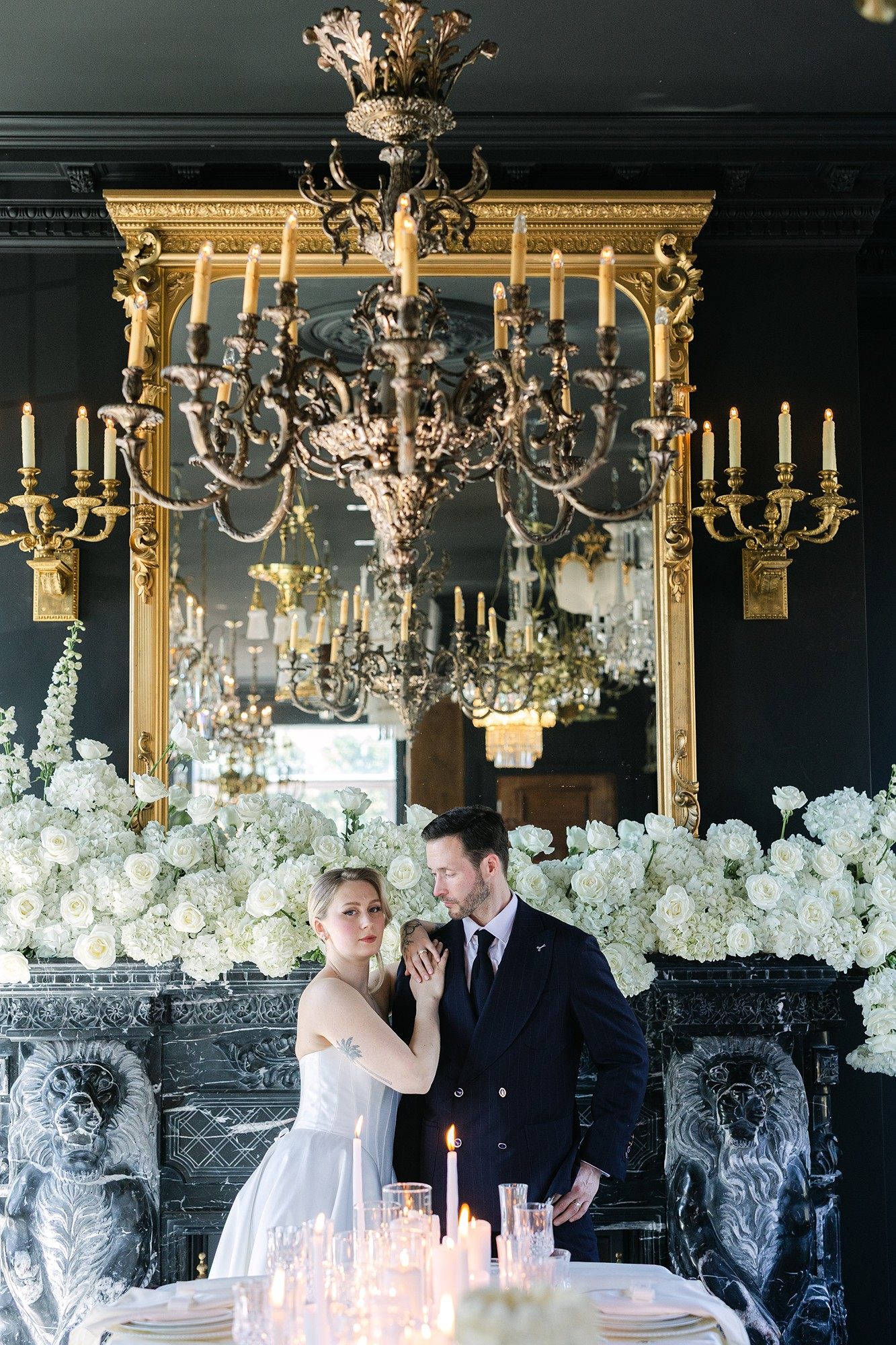 Couple de mariés devant le miroir doré et les fleurs blanches