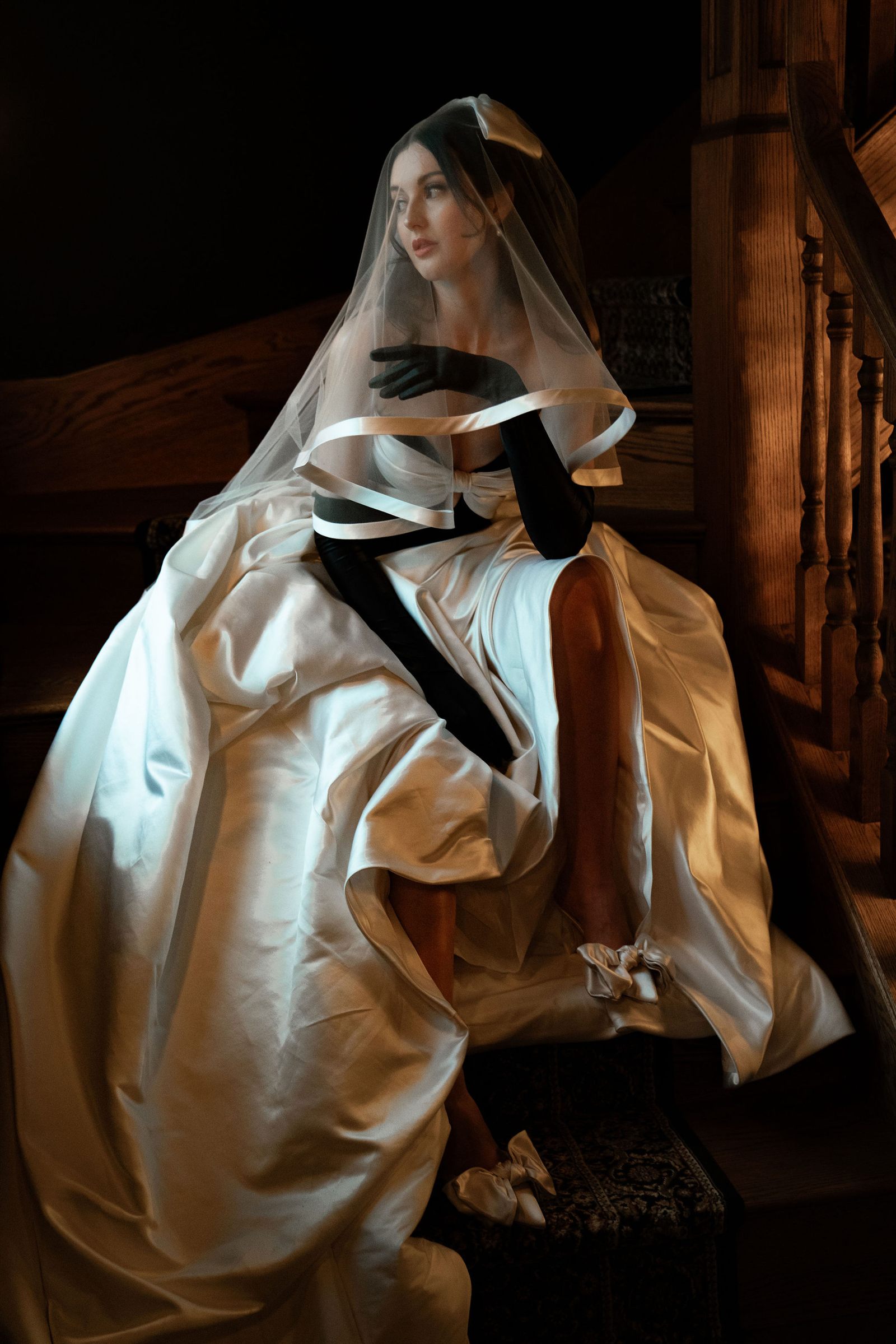 Mariée en robe d'apparat assise dans l'escalier du manoir