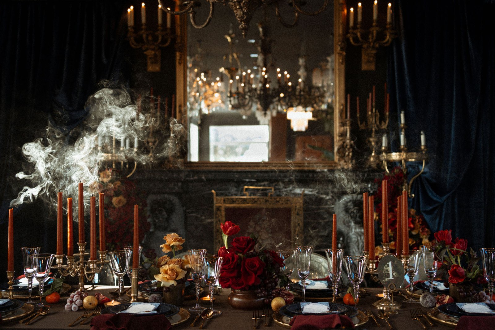 Table de mariage dressée devant le foyer et le grand miroir doré du Manoir Blackswan, chandelles rouille et roses rouges