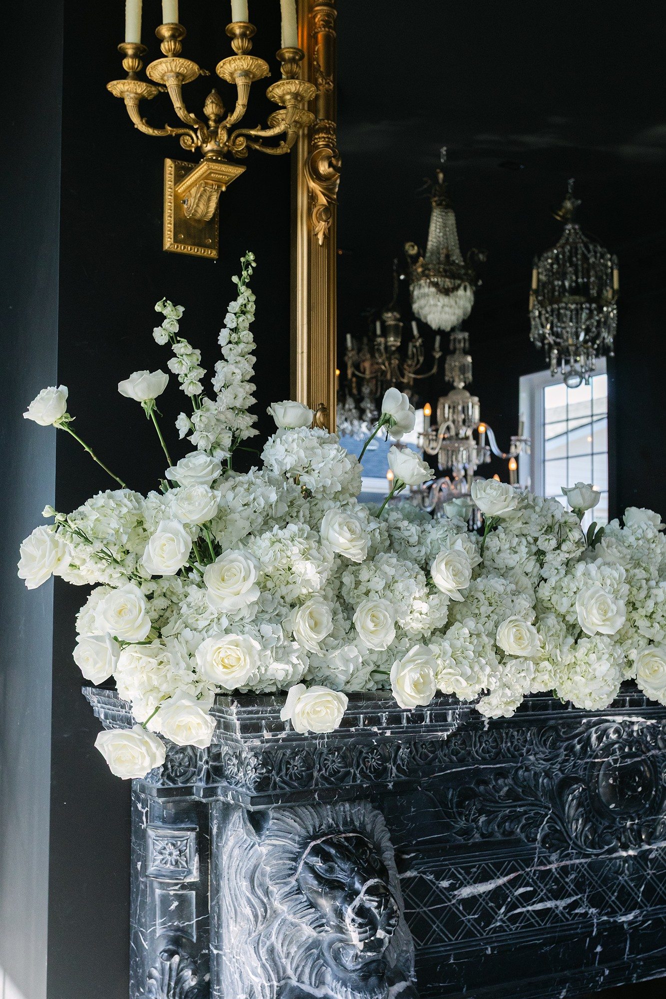 Roses et hortensias blancs sur la cheminée de marbre noir du Manoir Blackswan