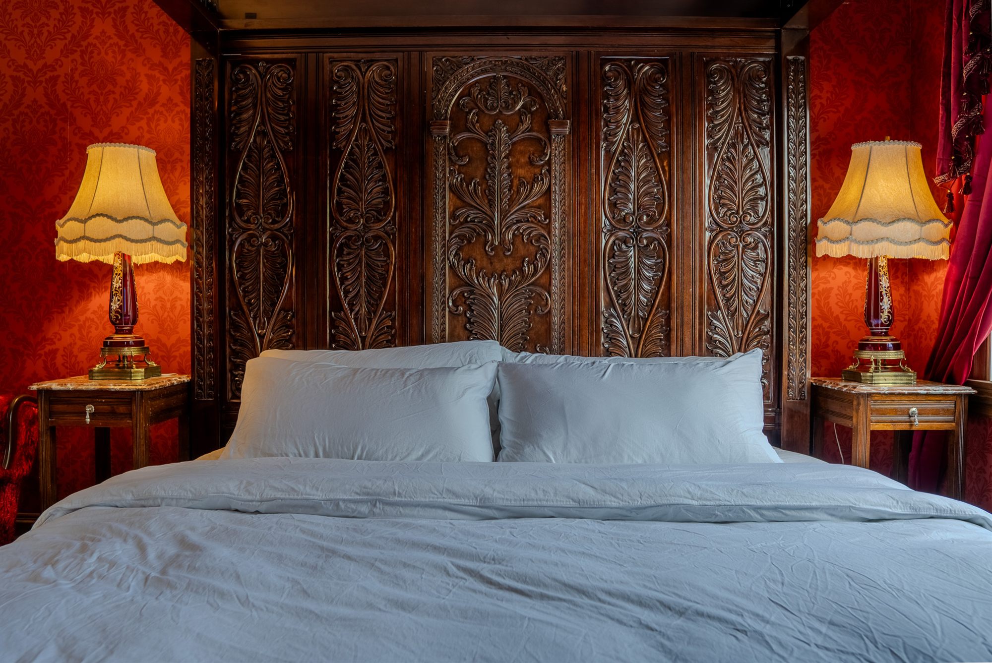 Une chambre du Manoir Blackswan, tête de lit sculptée et tenture damassée